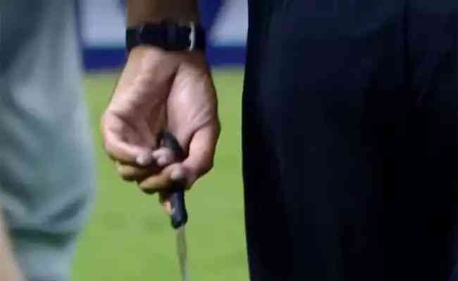 Câmera de TV mostra o árbitro com a faca encontrada no gramado após invasão de torcedores