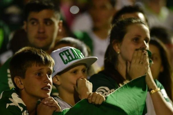 Foi na Arena ndio Cond que a Chapecoense deixou o 'anonimato' para ganhar os coraes de todos os brasileiros. Em seu estdio, o Verdo do Oeste mostrou toda sua valentia ao permanecer por trs anos seguidos na Srie A e, consequentemente, alcanar a deciso da Copa Sul-Americana. Pelo caminho ficaram gigantes como os argentinos Independiente e San Lorenzo e o colombiano Junior Barranquilla. Restava apenas o poderoso Atltico Nacional, melhor clube da atualidade na Amrica do Sul. Dentro de campo, a Chape no pde dar sequncia  sua bravura, pois acabou vitimada por um acidente areo que matou quase toda sua delegao nas proximidades de Medelln, na Colmbia. Mas, se depender do amor de uma multido, o clube renascer. A mesma Arena Cond que foi palco de trs acessos - da Srie D para a C, em 2009; da C para a B, em 2012; e da B para a A, em 2013 -  o local onde milhares de torcedores prestam as ltimas homenagens aos falecidos. Sempre, claro, com a esperana de que a agremiao se reerguer e dar continuidade ao belo trabalho recente. Vamos, vamos Chape!!! (CRDITO DAS IMAGENS: DOUGLAS MAGNO/AFP)