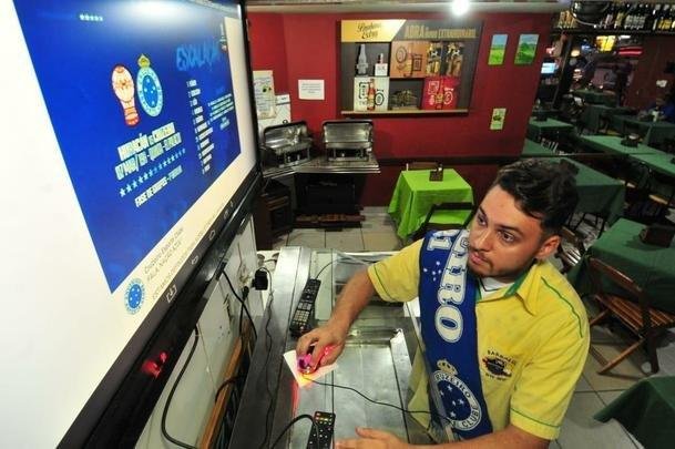 Em bares de Belo Horizonte, torcedores do Cruzeiro tiveram que recorrer a celulares e notebooks para assistir ao duelo com o Huracn, pela Copa Libertadores, via Facebook. Transmisses com o tradicional telo oferecidas por alguns estabelecimentos travaram muito e at foram tiradas do ar. Na verso mobile, resultado foi melhor. Na foto, Eduardo Arajo, funcionrio do Barbazul, preparando a transmisso.