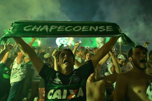 Foi na Arena ndio Cond que a Chapecoense deixou o 'anonimato' para ganhar os coraes de todos os brasileiros. Em seu estdio, o Verdo do Oeste mostrou toda sua valentia ao permanecer por trs anos seguidos na Srie A e, consequentemente, alcanar a deciso da Copa Sul-Americana. Pelo caminho ficaram gigantes como os argentinos Independiente e San Lorenzo e o colombiano Junior Barranquilla. Restava apenas o poderoso Atltico Nacional, melhor clube da atualidade na Amrica do Sul. Dentro de campo, a Chape no pde dar sequncia  sua bravura, pois acabou vitimada por um acidente areo que matou quase toda sua delegao nas proximidades de Medelln, na Colmbia. Mas, se depender do amor de uma multido, o clube renascer. A mesma Arena Cond que foi palco de trs acessos - da Srie D para a C, em 2009; da C para a B, em 2012; e da B para a A, em 2013 -  o local onde milhares de torcedores prestam as ltimas homenagens aos falecidos. Sempre, claro, com a esperana de que a agremiao se reerguer e dar continuidade ao belo trabalho recente. Vamos, vamos Chape!!! (CRDITO DAS IMAGENS: NELSON ALMEIDA/AFP)