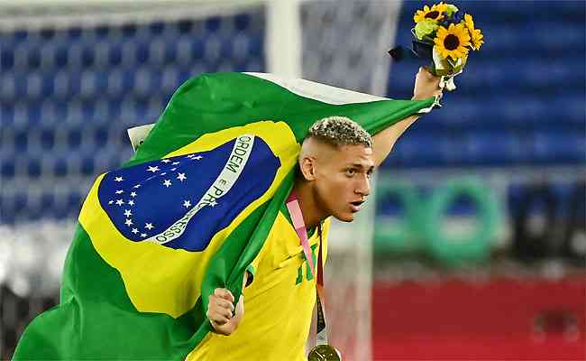 Richarlison festeja o ouro em Yokohama com a bandeira do Brasil: carta por mais apoio a atletas