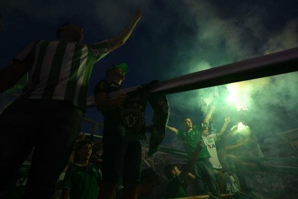 Foi na Arena ndio Cond que a Chapecoense deixou o 'anonimato' para ganhar os coraes de todos os brasileiros. Em seu estdio, o Verdo do Oeste mostrou toda sua valentia ao permanecer por trs anos seguidos na Srie A e, consequentemente, alcanar a deciso da Copa Sul-Americana. Pelo caminho ficaram gigantes como os argentinos Independiente e San Lorenzo e o colombiano Junior Barranquilla. Restava apenas o poderoso Atltico Nacional, melhor clube da atualidade na Amrica do Sul. Dentro de campo, a Chape no pde dar sequncia  sua bravura, pois acabou vitimada por um acidente areo que matou quase toda sua delegao nas proximidades de Medelln, na Colmbia. Mas, se depender do amor de uma multido, o clube renascer. A mesma Arena Cond que foi palco de trs acessos - da Srie D para a C, em 2009; da C para a B, em 2012; e da B para a A, em 2013 -  o local onde milhares de torcedores prestam as ltimas homenagens aos falecidos. Sempre, claro, com a esperana de que a agremiao se reerguer e dar continuidade ao belo trabalho recente. Vamos, vamos Chape!!! (CRDITO DAS IMAGENS: NELSON ALMEIDA/AFP)