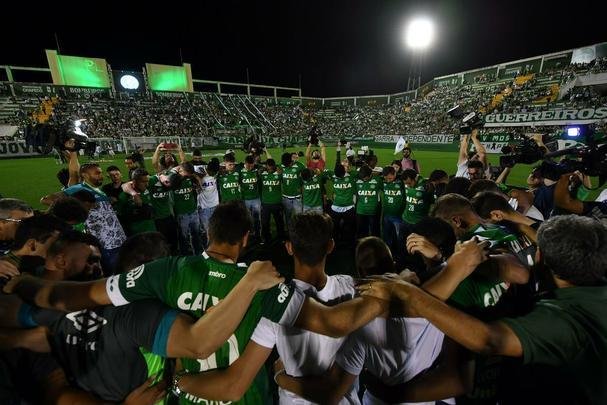 Foi na Arena ndio Cond que a Chapecoense deixou o 'anonimato' para ganhar os coraes de todos os brasileiros. Em seu estdio, o Verdo do Oeste mostrou toda sua valentia ao permanecer por trs anos seguidos na Srie A e, consequentemente, alcanar a deciso da Copa Sul-Americana. Pelo caminho ficaram gigantes como os argentinos Independiente e San Lorenzo e o colombiano Junior Barranquilla. Restava apenas o poderoso Atltico Nacional, melhor clube da atualidade na Amrica do Sul. Dentro de campo, a Chape no pde dar sequncia  sua bravura, pois acabou vitimada por um acidente areo que matou quase toda sua delegao nas proximidades de Medelln, na Colmbia. Mas, se depender do amor de uma multido, o clube renascer. A mesma Arena Cond que foi palco de trs acessos - da Srie D para a C, em 2009; da C para a B, em 2012; e da B para a A, em 2013 -  o local onde milhares de torcedores prestam as ltimas homenagens aos falecidos. Sempre, claro, com a esperana de que a agremiao se reerguer e dar continuidade ao belo trabalho recente. Vamos, vamos Chape!!! (CRDITO DAS IMAGENS: NELSON ALMEIDA/AFP)