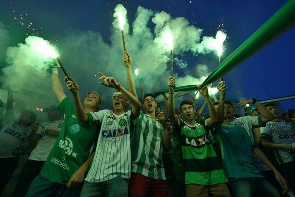 Foi na Arena ndio Cond que a Chapecoense deixou o 'anonimato' para ganhar os coraes de todos os brasileiros. Em seu estdio, o Verdo do Oeste mostrou toda sua valentia ao permanecer por trs anos seguidos na Srie A e, consequentemente, alcanar a deciso da Copa Sul-Americana. Pelo caminho ficaram gigantes como os argentinos Independiente e San Lorenzo e o colombiano Junior Barranquilla. Restava apenas o poderoso Atltico Nacional, melhor clube da atualidade na Amrica do Sul. Dentro de campo, a Chape no pde dar sequncia  sua bravura, pois acabou vitimada por um acidente areo que matou quase toda sua delegao nas proximidades de Medelln, na Colmbia. Mas, se depender do amor de uma multido, o clube renascer. A mesma Arena Cond que foi palco de trs acessos - da Srie D para a C, em 2009; da C para a B, em 2012; e da B para a A, em 2013 -  o local onde milhares de torcedores prestam as ltimas homenagens aos falecidos. Sempre, claro, com a esperana de que a agremiao se reerguer e dar continuidade ao belo trabalho recente. Vamos, vamos Chape!!! (CRDITO DAS IMAGENS: NELSON ALMEIDA/AFP)