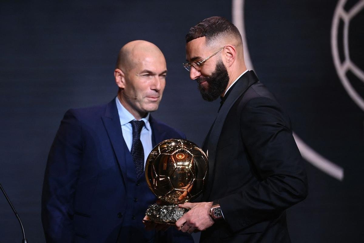 Benzema, do Real Madrid, foi eleito o melhor jogador do mundo de 2022 no prmio Bola de Ouro, da Revista France Football. Ele recebeu a trofu das mos de Zinedine Zidane