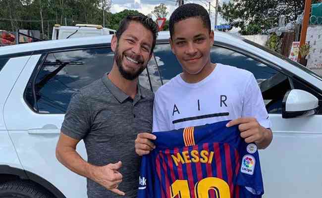 Vitor Roque ao lado de Ehler Pessoa e com uma camisa do Barcelona autografada por Messi. O presente foi dado por Cury