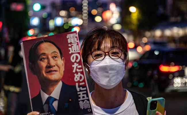 Ativista contrria  realizao da Olimpada exibe imagem do primeiro-ministro Yoshihide Suga durante marcha em Tquio na sexta-feira