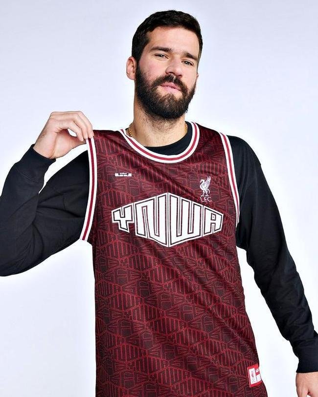 A jersey de basquete tem o vermelho como base com diversos losangos que formam as siglas 'YNWA' e 'SFC' em preto 